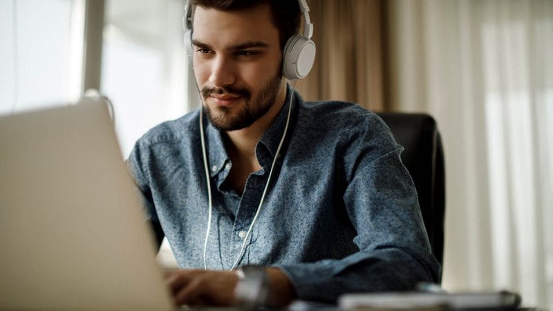 Young man wearing headphones and using a laptop